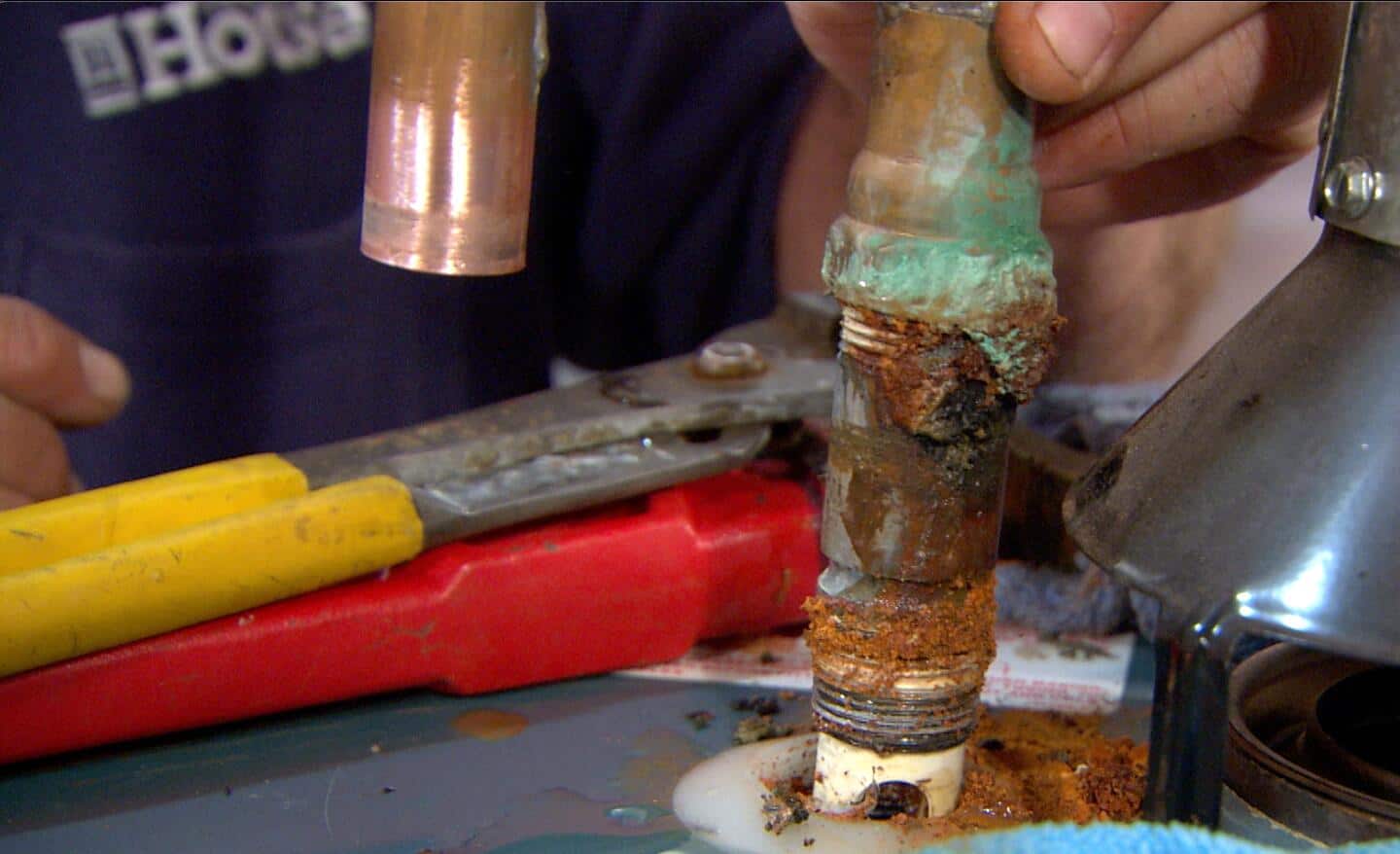 Someone removing a rusted part of a water heater.