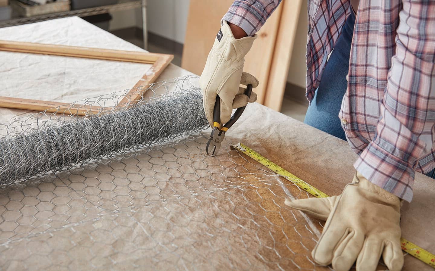 A person measures and cuts chicken wire. A person measures and cuts chicken wire.