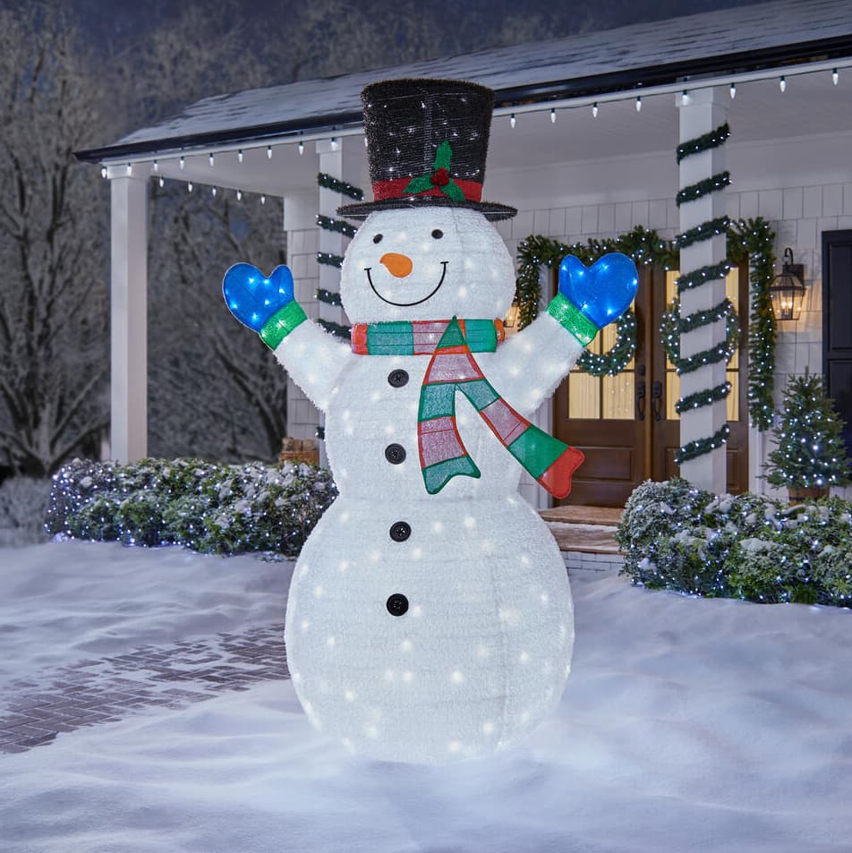 Lighted snowmen on parade with picket fence in background at
