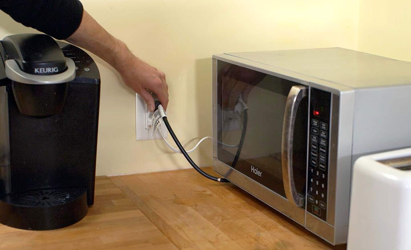 A person unplugging a microwave. 
