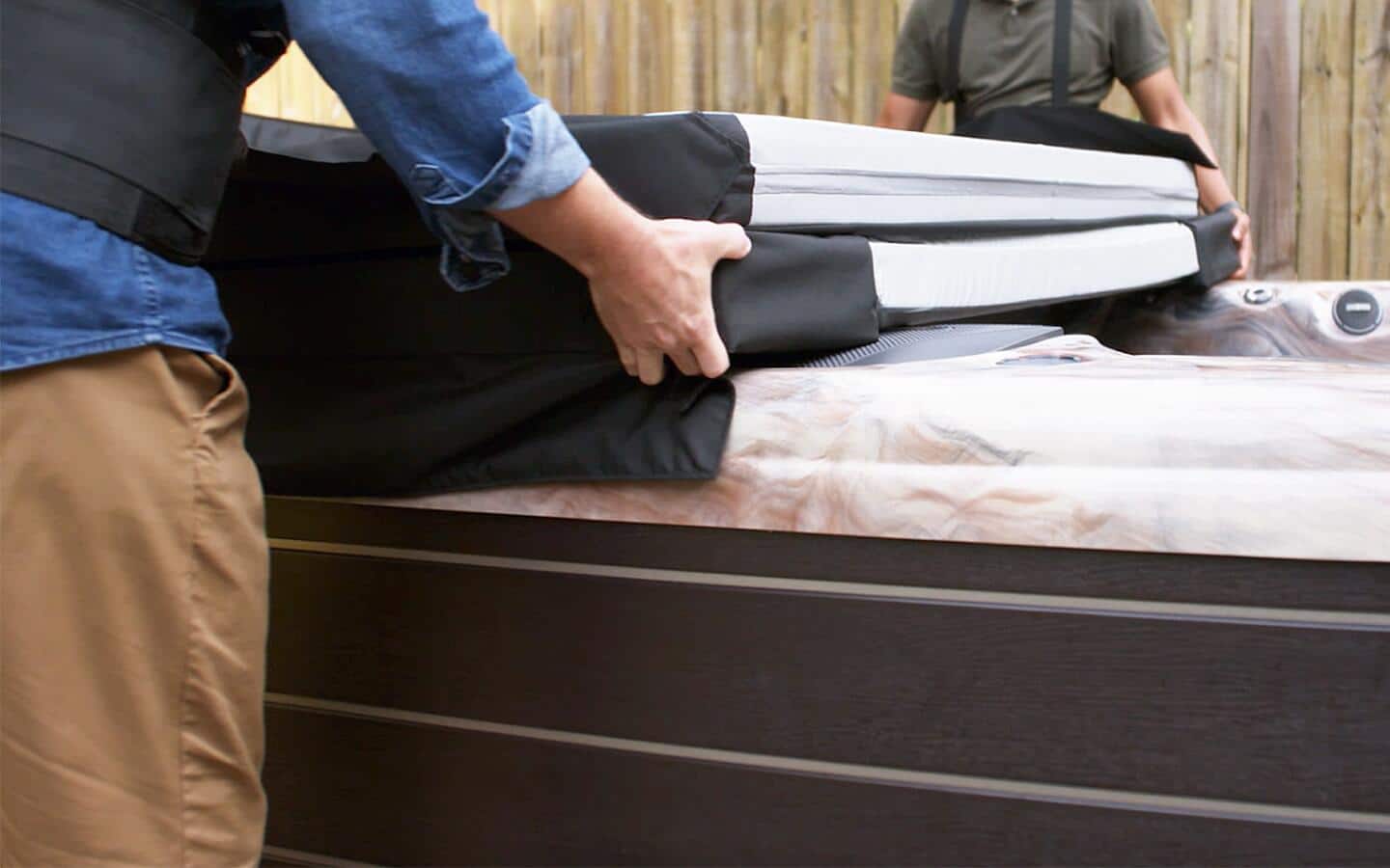 A hot tub cover being placed on top of a hot tub.