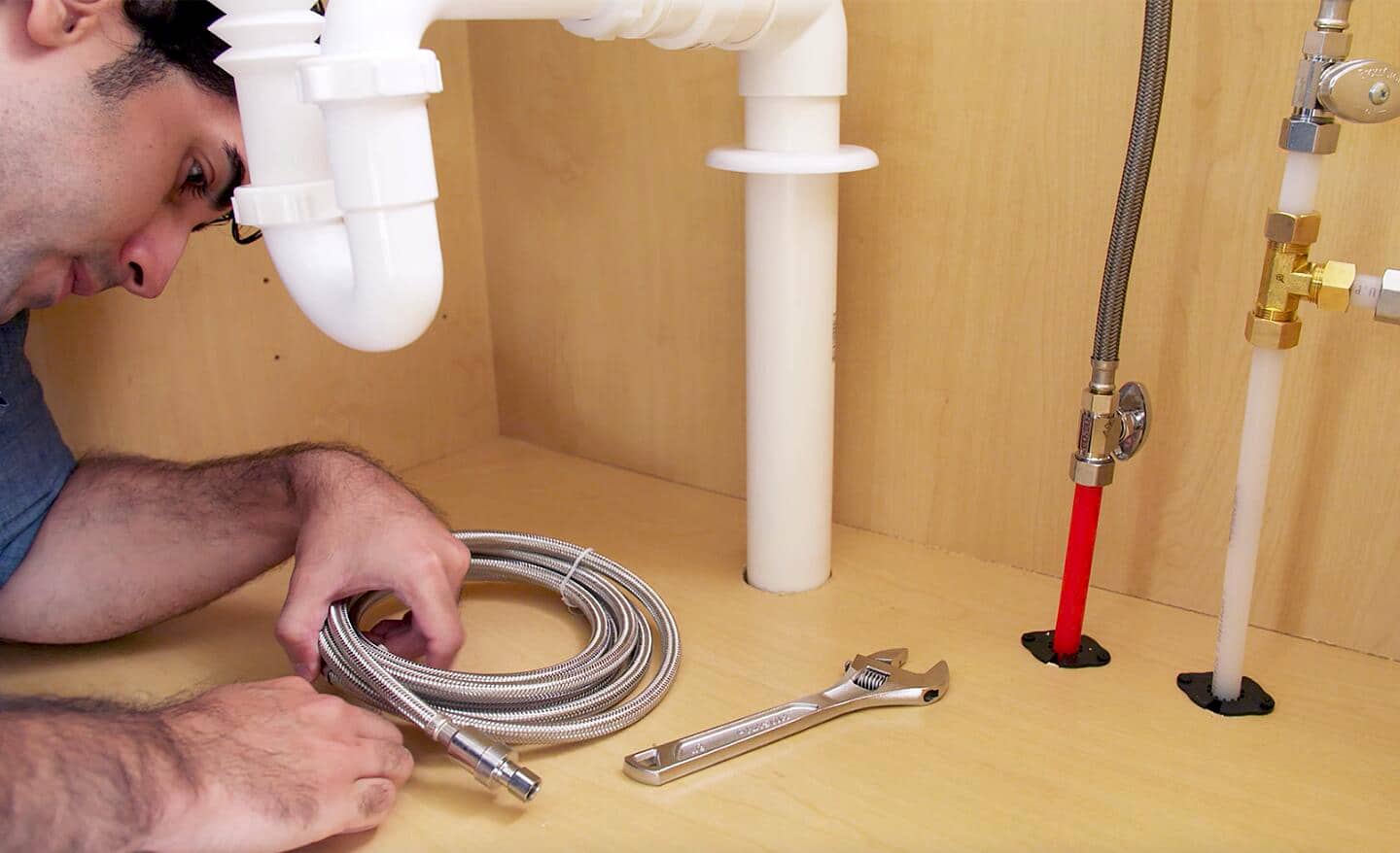A person under the sink preparing to run a galvanized steel water line.