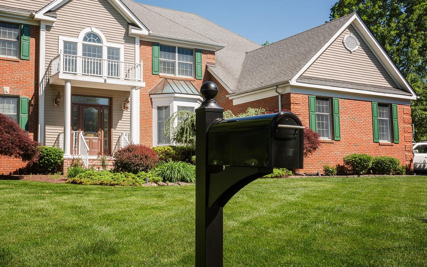 An average-size mailbox installed outside a large brick home. An average-size mailbox installed outside a large brick home.