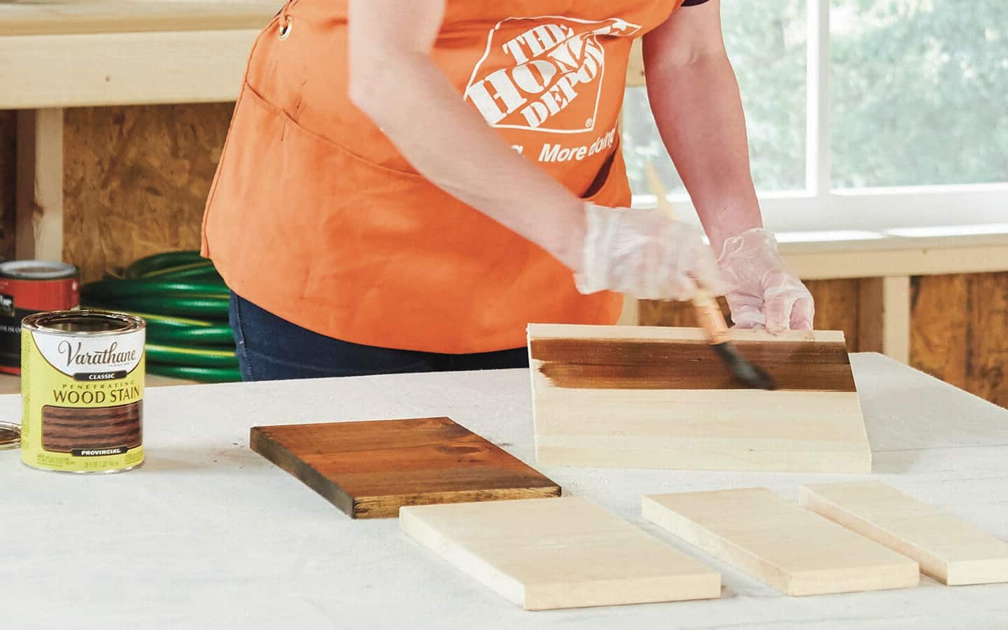 An individual applies brown stain to wood for a sofa table.