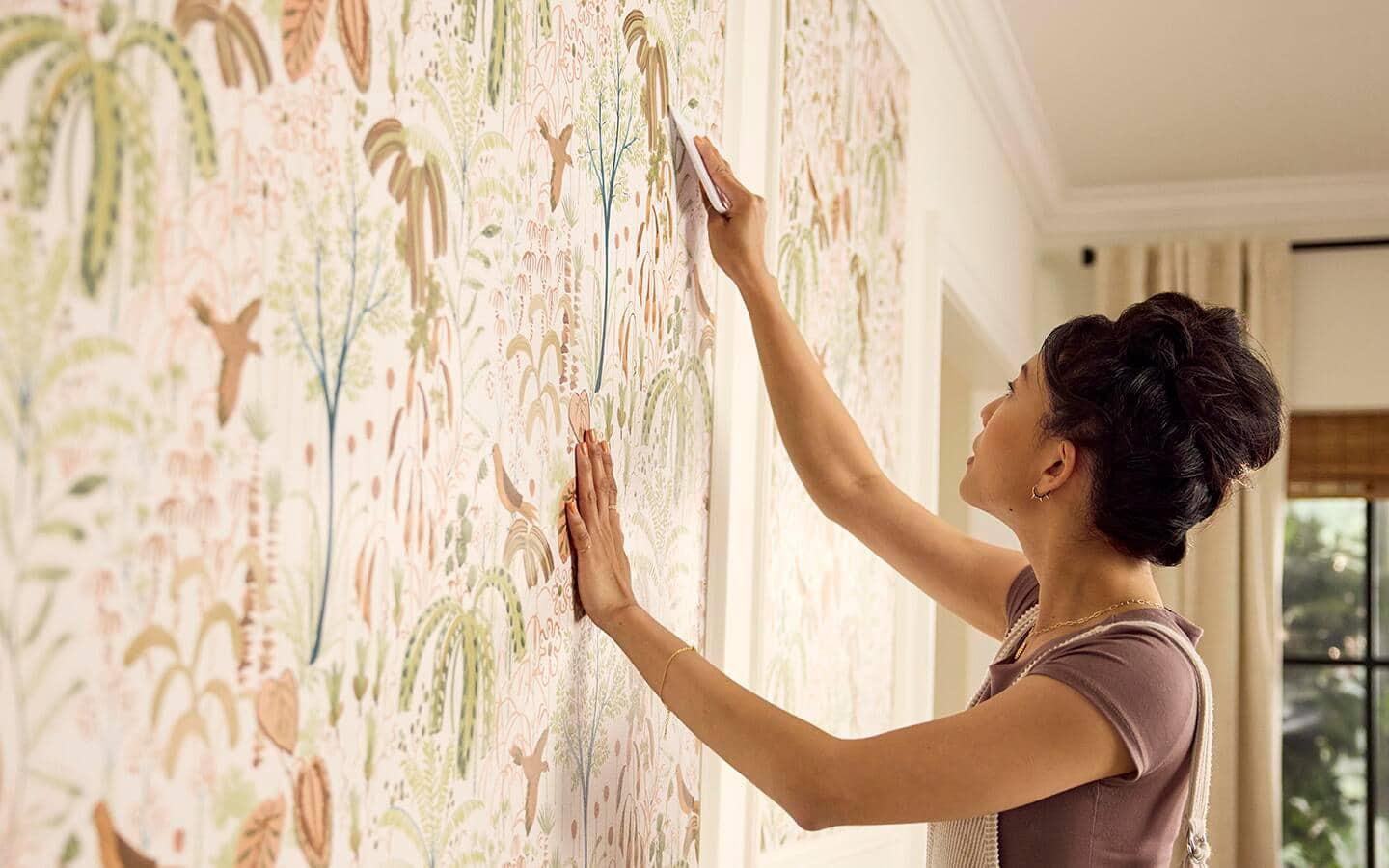 A person applying wallpaper to a wall in a living room space A person applying wallpaper to a wall in a living room space