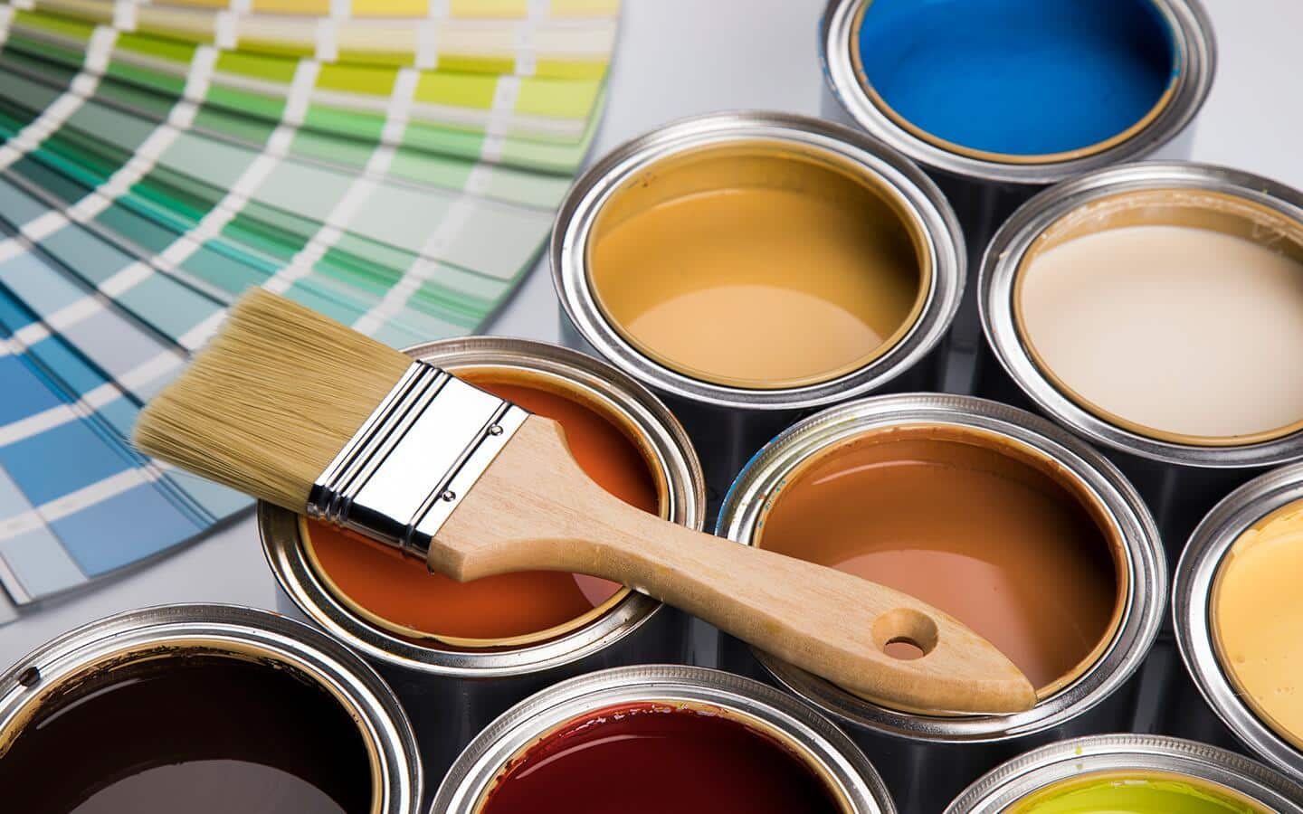 Multiple open paint cans and color samples with a paintbrush.