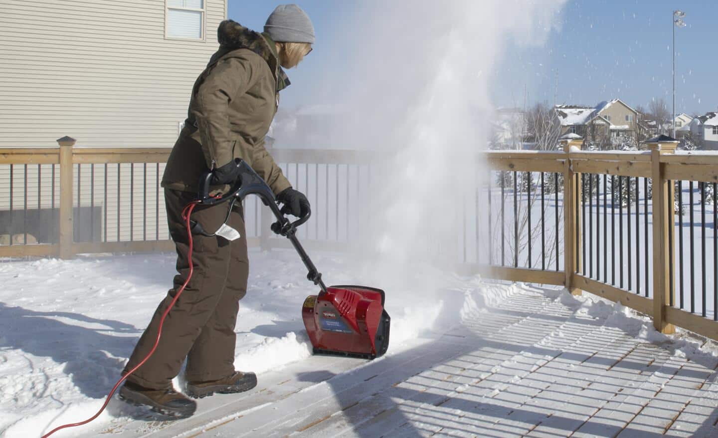 A person uses an electric snow shovel to clear snow. A person uses an electric snow shovel to clear snow.