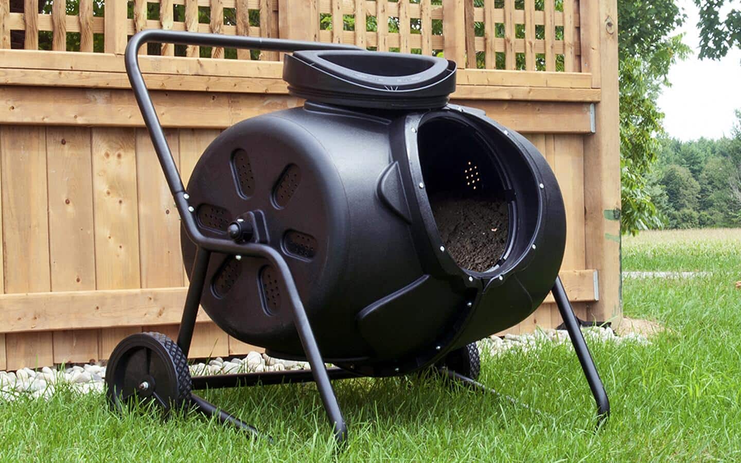 A black continuous composter in a backyard.