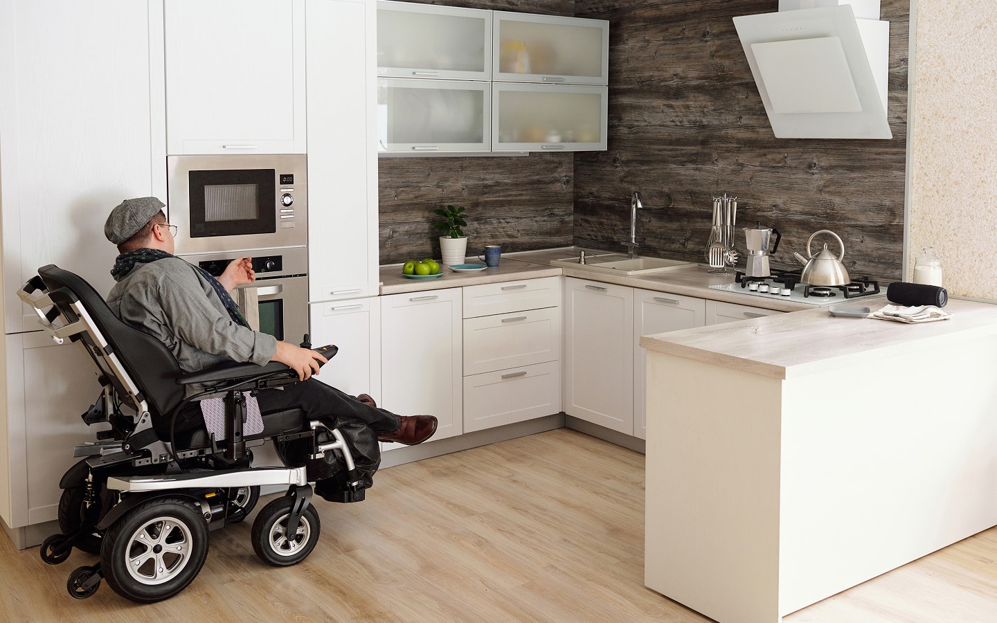 A person in a wheelchair moves through an ADA-compliant kitchen.