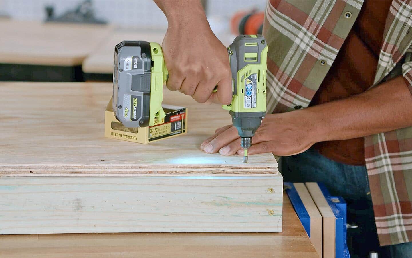 A person using a cordless drill on the base of a dog house.