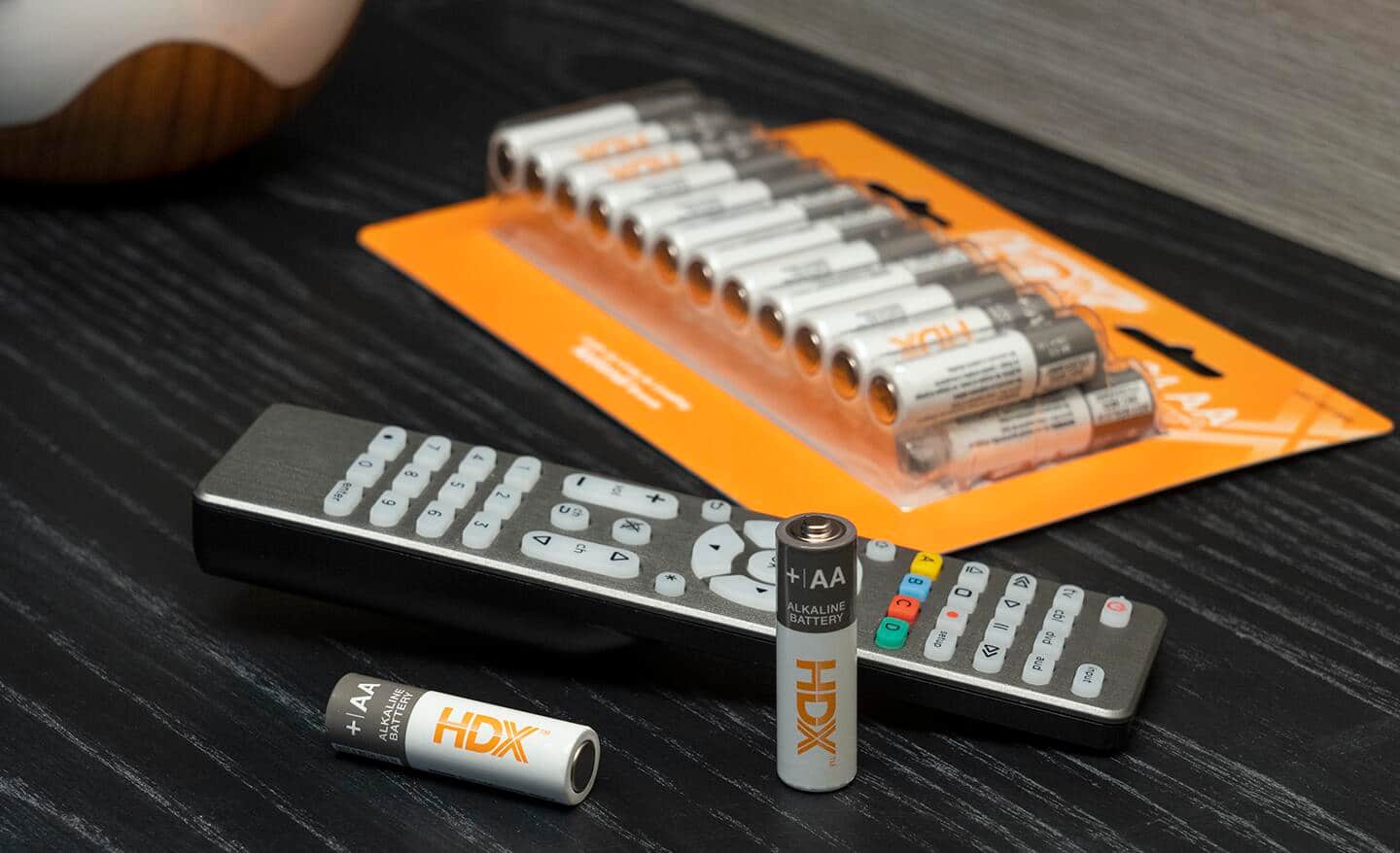 A package of AA batteries lying next to a TV remote control.
