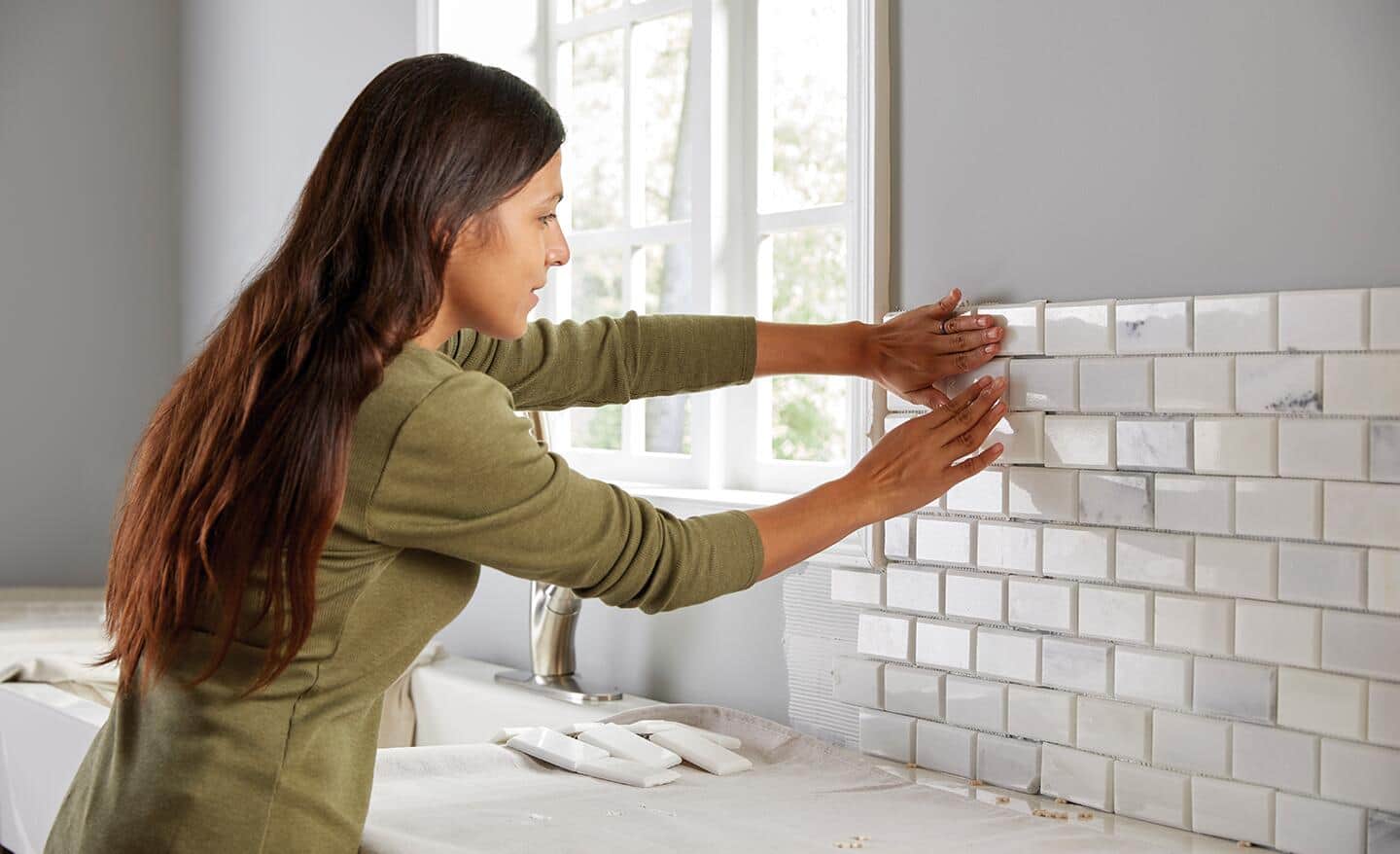 A person laying tile on a wall.
