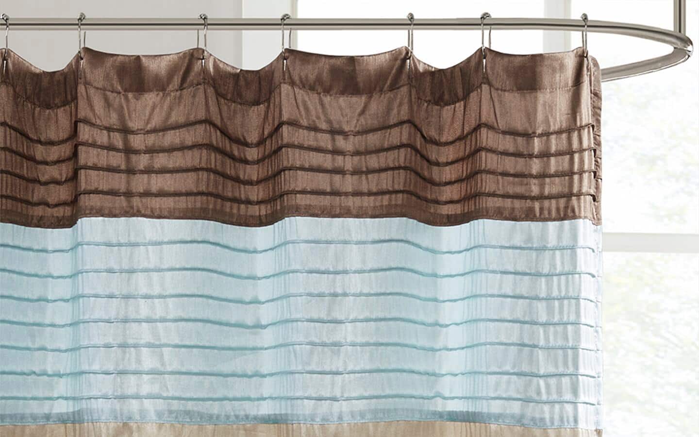 A shower curtain with teal and brown stripes hanging on a circular, silver shower rod.