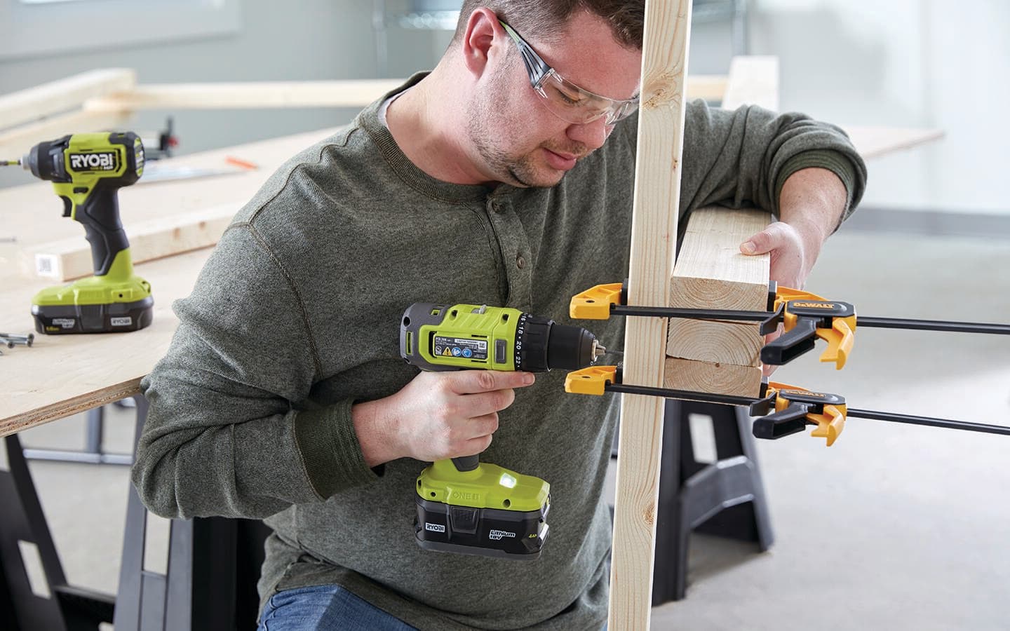 A man with a cordless screwdriver attaches wooden feet to a photo booth's frame. A man with a cordless screwdriver attaches wooden feet to a photo booth's frame.