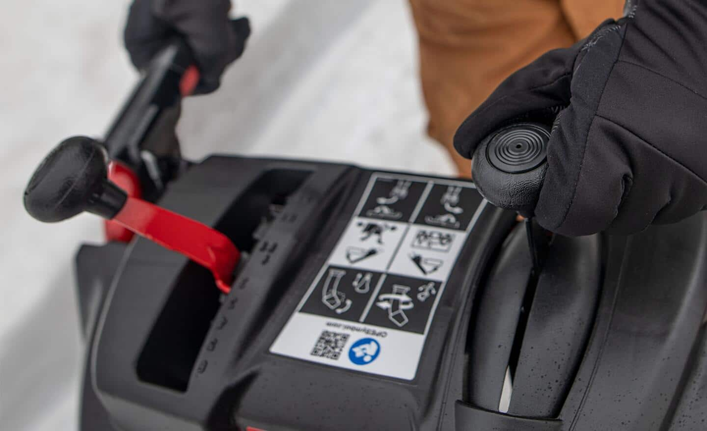 A close-up of a person preparing to use a snow blower.