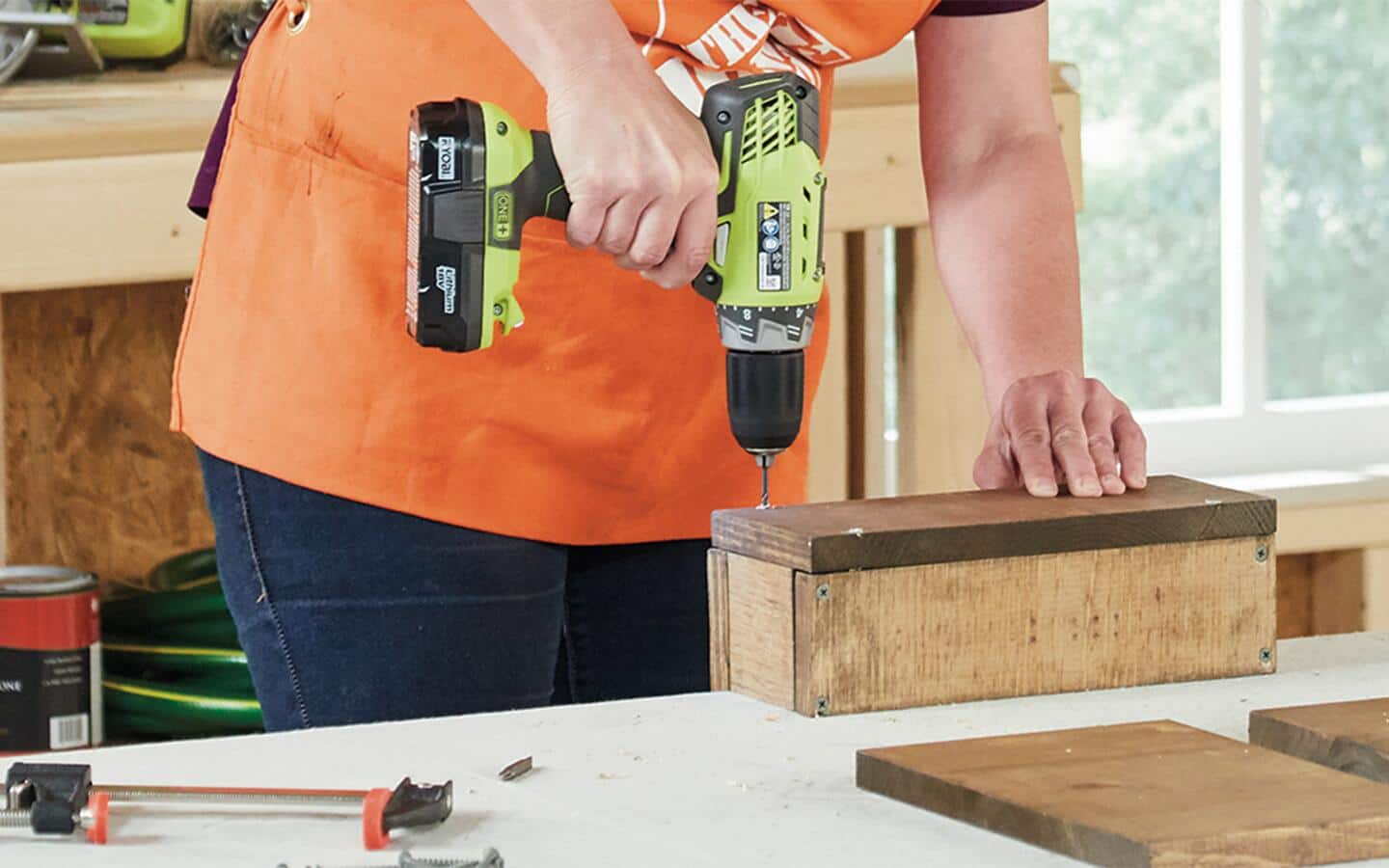 Someone uses a cordless drill to attach a sofa table's wood pieces together.