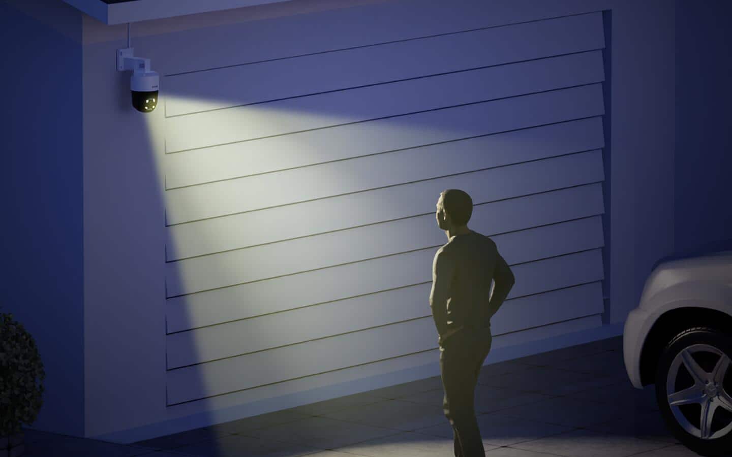 A person standing under an outdoor security camera and floodlight combo.