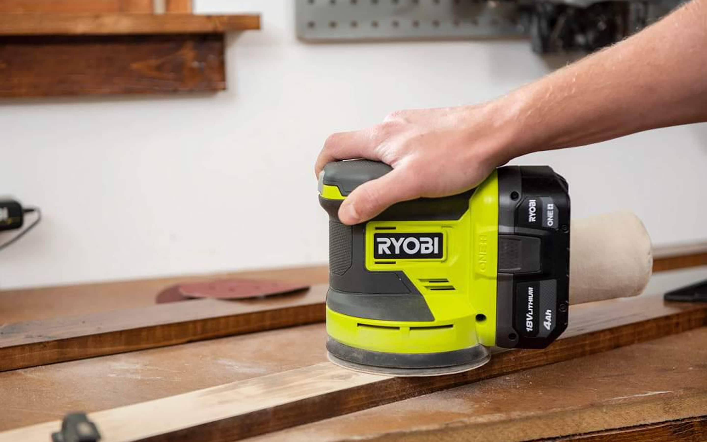 A person using a battery-operated sander.