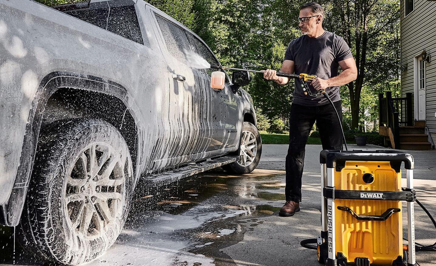 A man using a pressure washer to clean a truck.