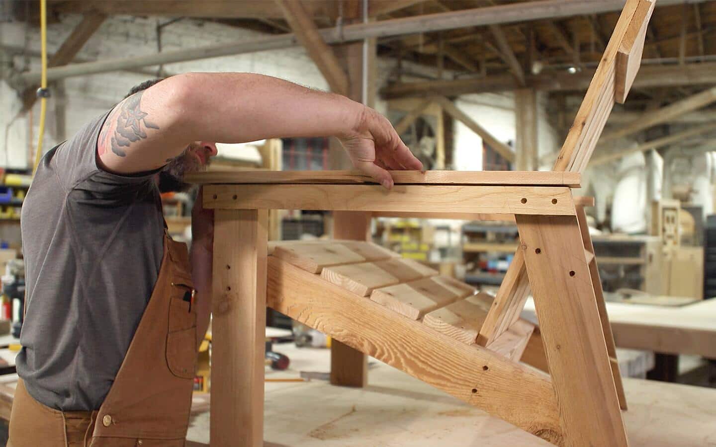 A person attaching an armrest to an Adirondack chair. A person attaching an armrest to an Adirondack chair.