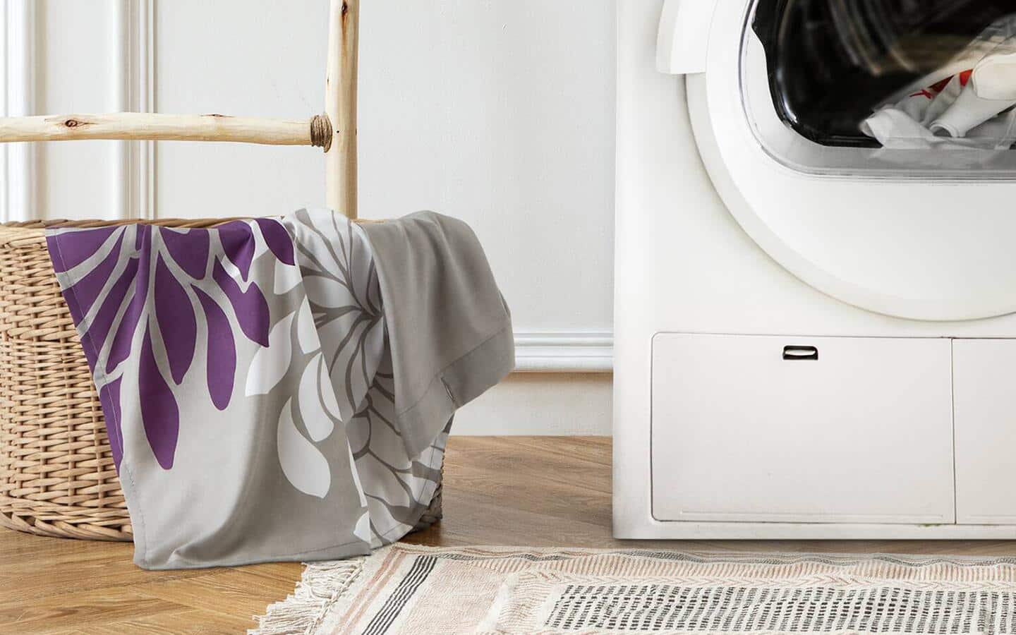 A fabric shower curtain in a stray laundry basket next to a white washer.