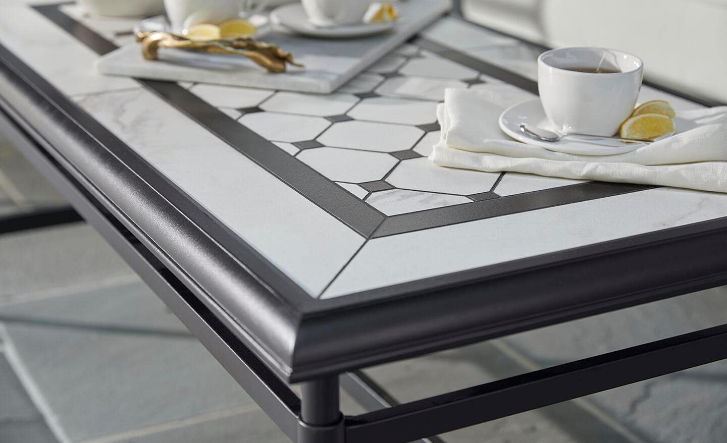 A reinforced aluminum coffee table with a gray and white tiled top on a patio.