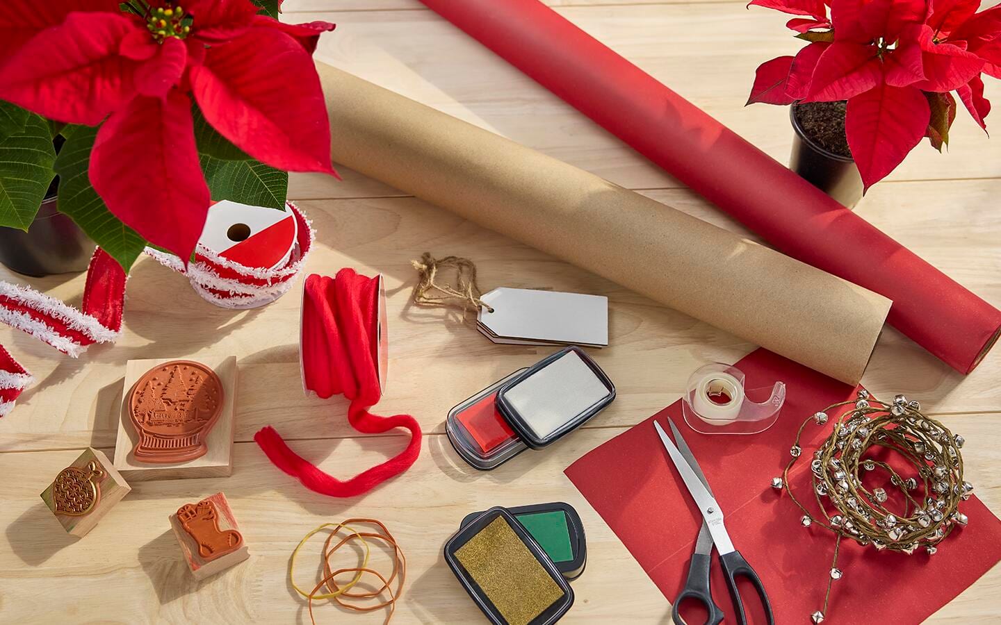 Brown kraft paper, poinsettia plants, tools and accessories for gift wrapping project on a table