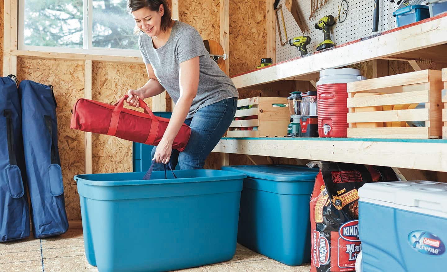 A woman puts items into a storage bin in a garage