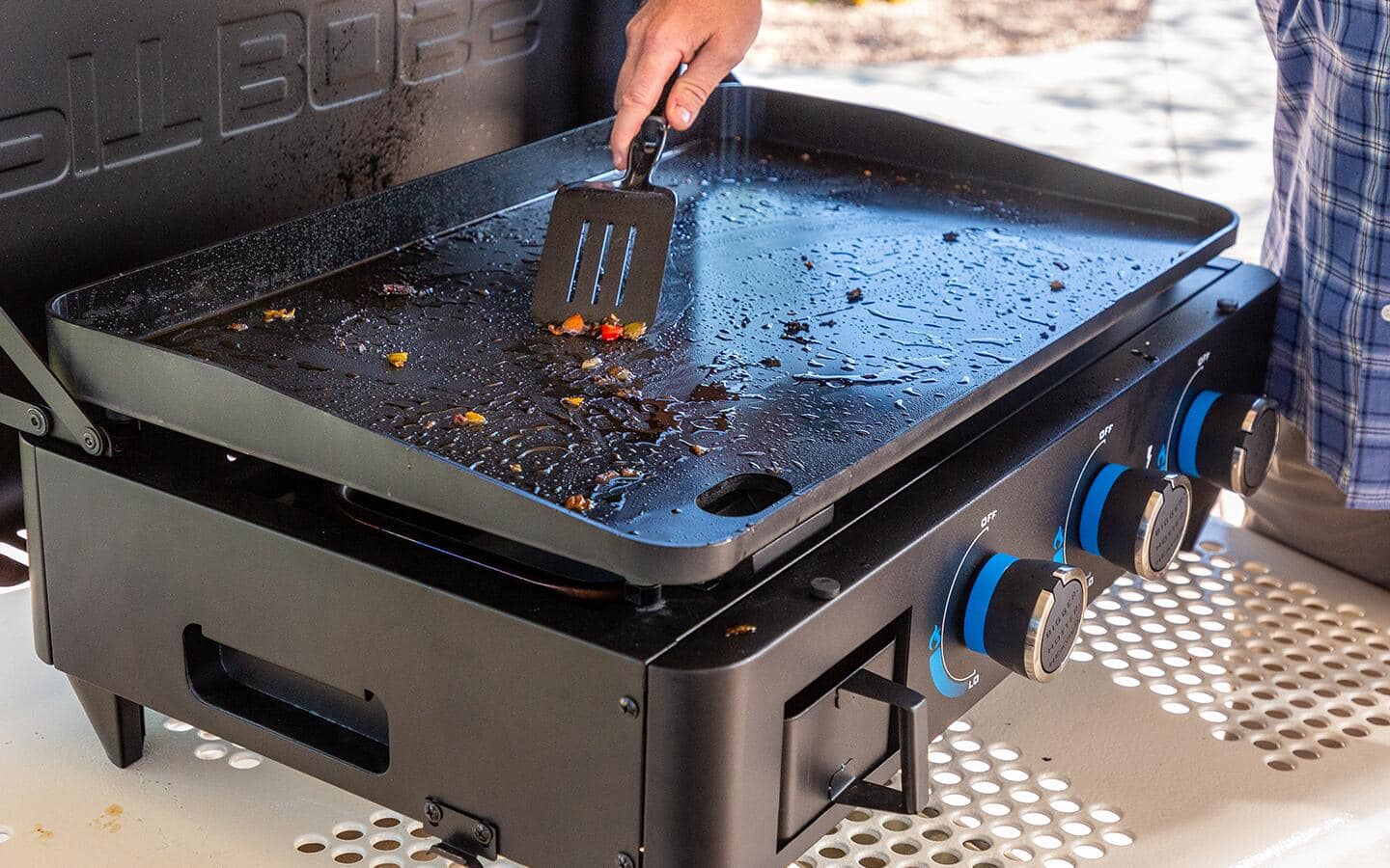 Someone scraping food off of a flat top grill. Someone scraping food off of a flat top grill.