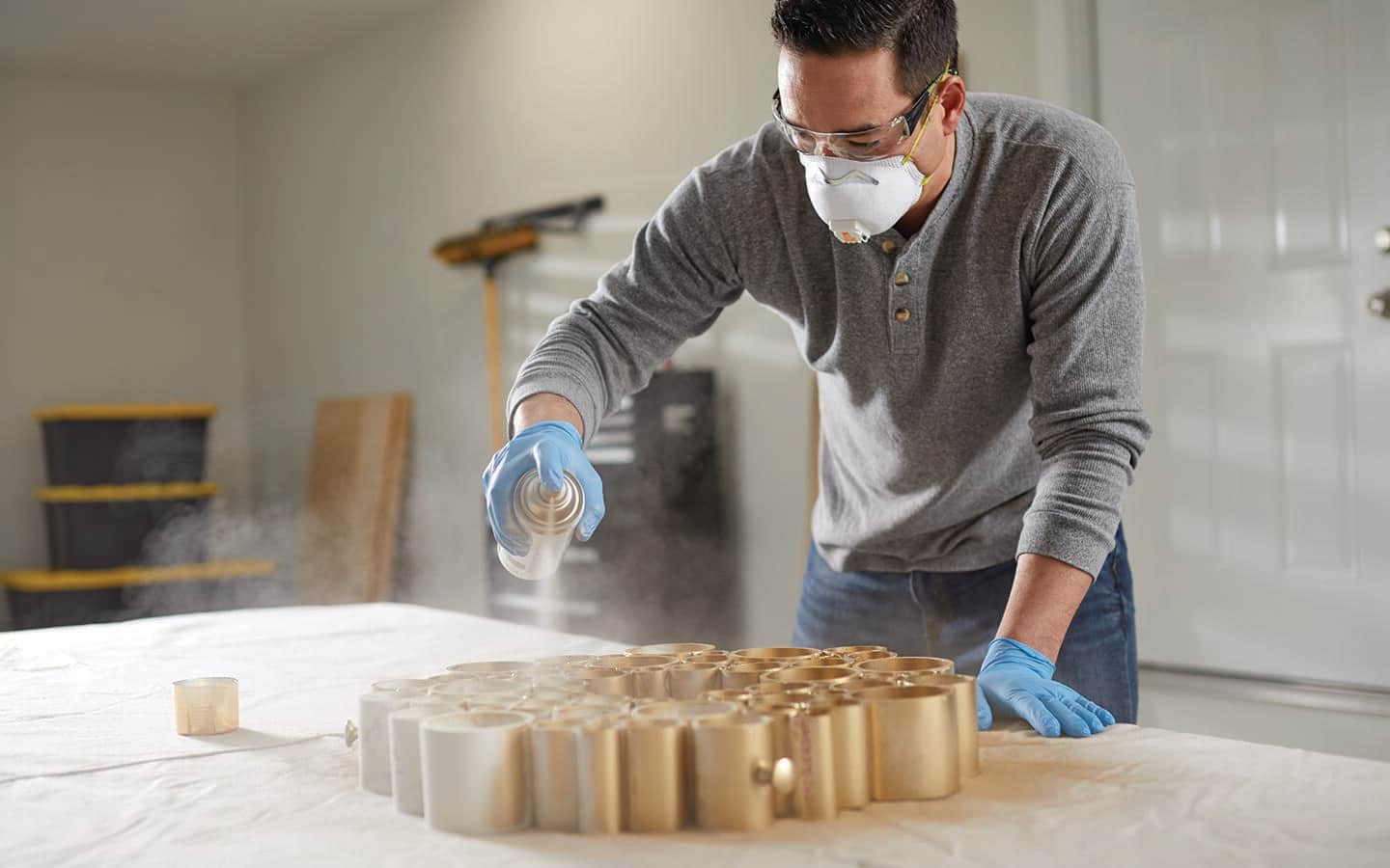 A man spray painting a PVC pipe holiday wreath gold. A man spray painting a PVC pipe holiday wreath gold.