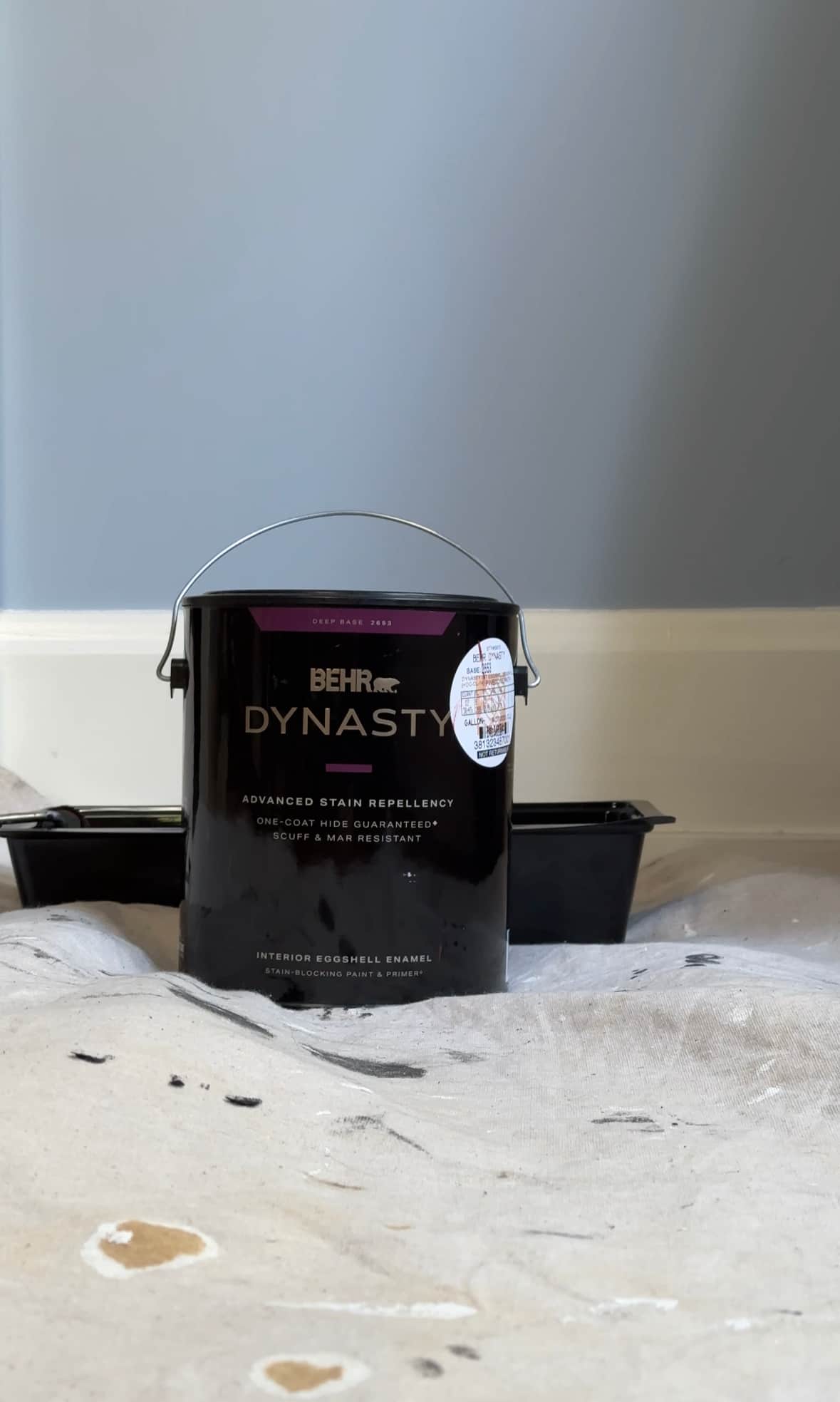 A can of Behr Dynasty in front of a wall.