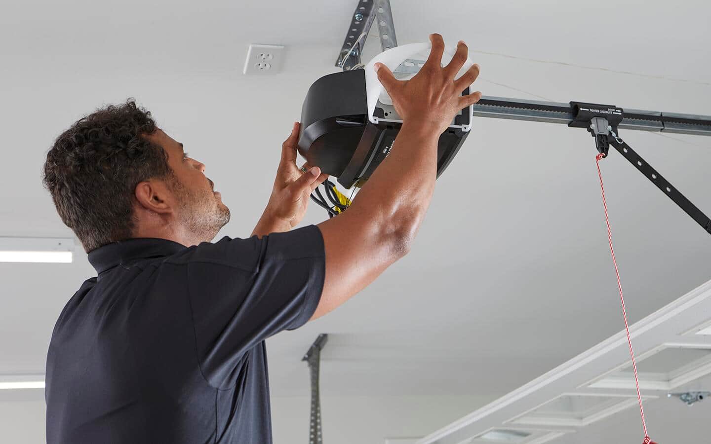 A person sets a garage door opener after installation.