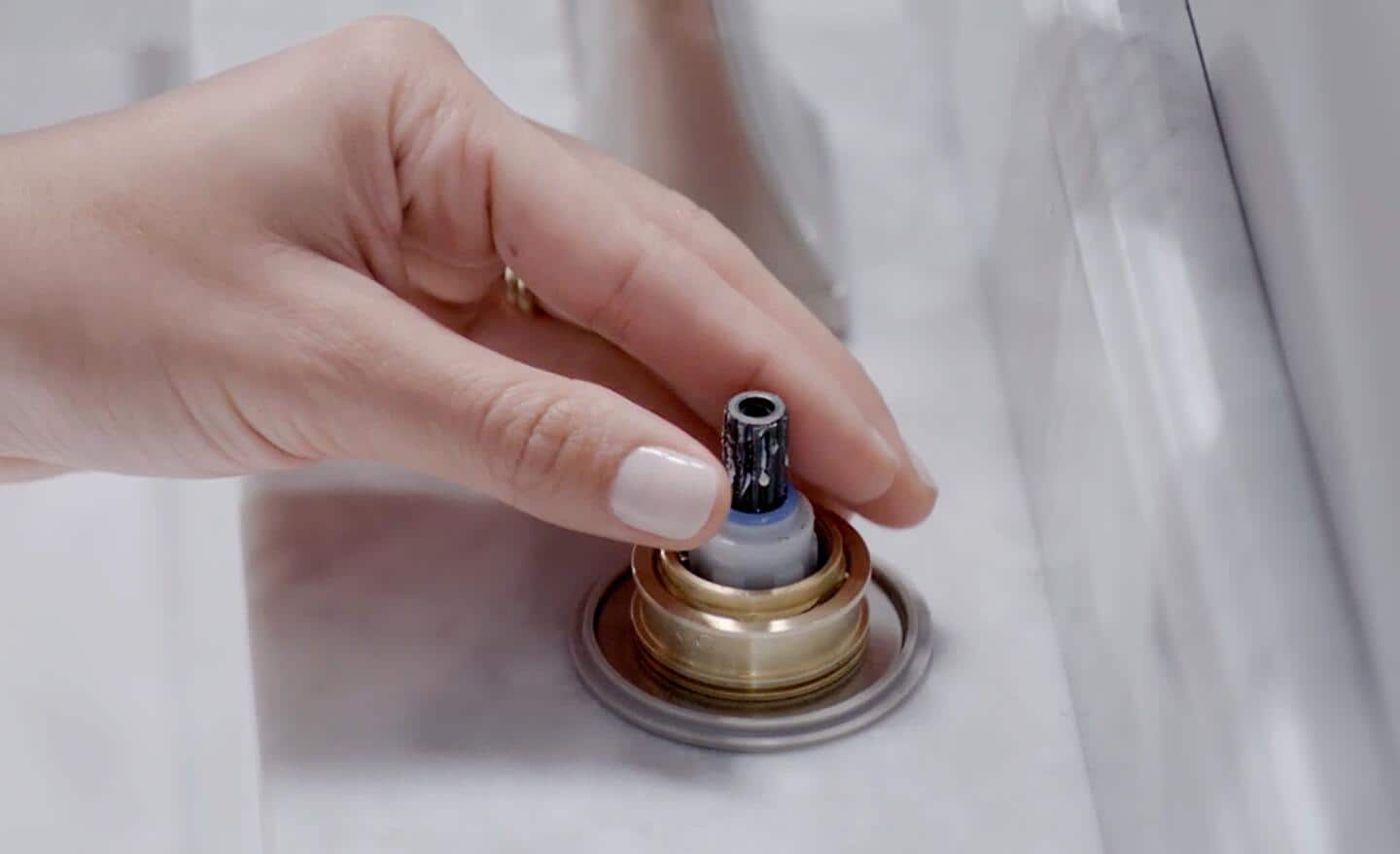 A person removes the cartridge from the sink to check it. 