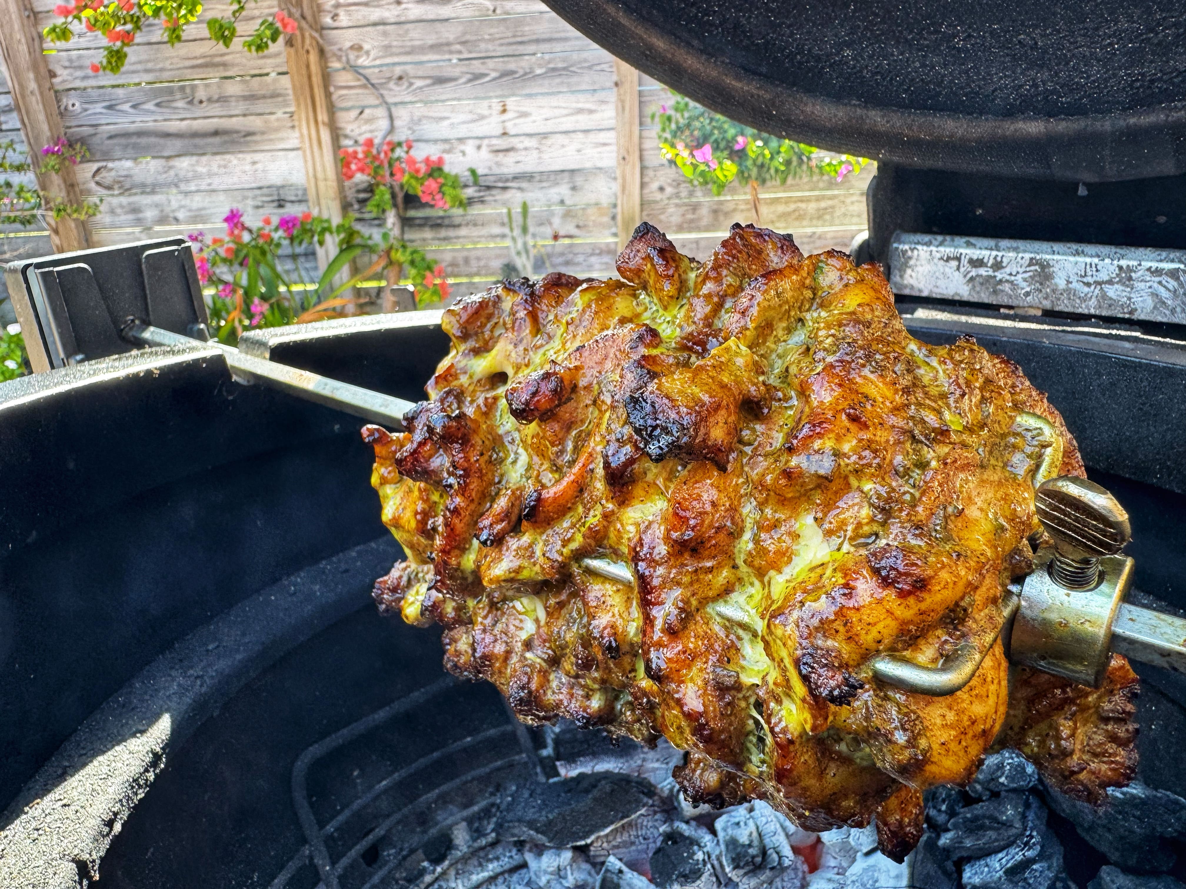 Cooked chicken on a spit in a grill.