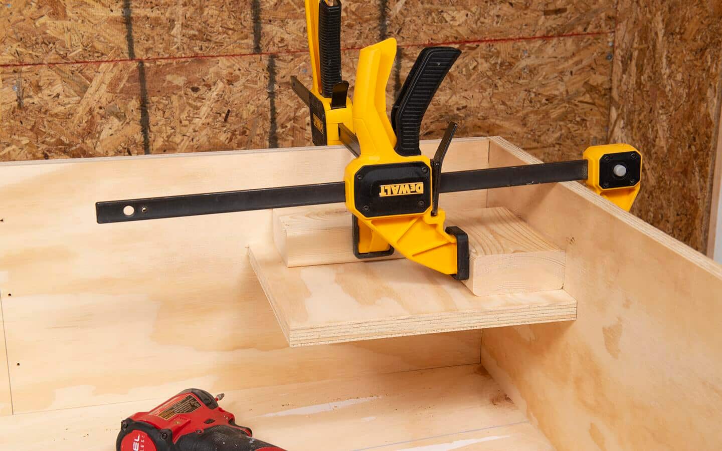 Woodworking clamps and a corner jig are used to hold a shelf in place as a shelving unit is being assembled.