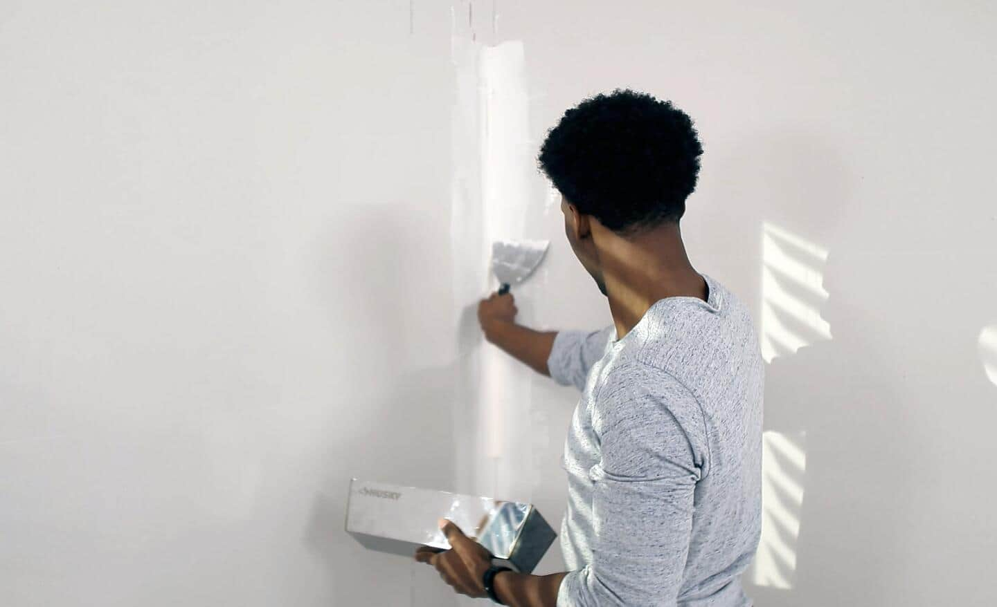 Someone applying drywall mud to a corner.