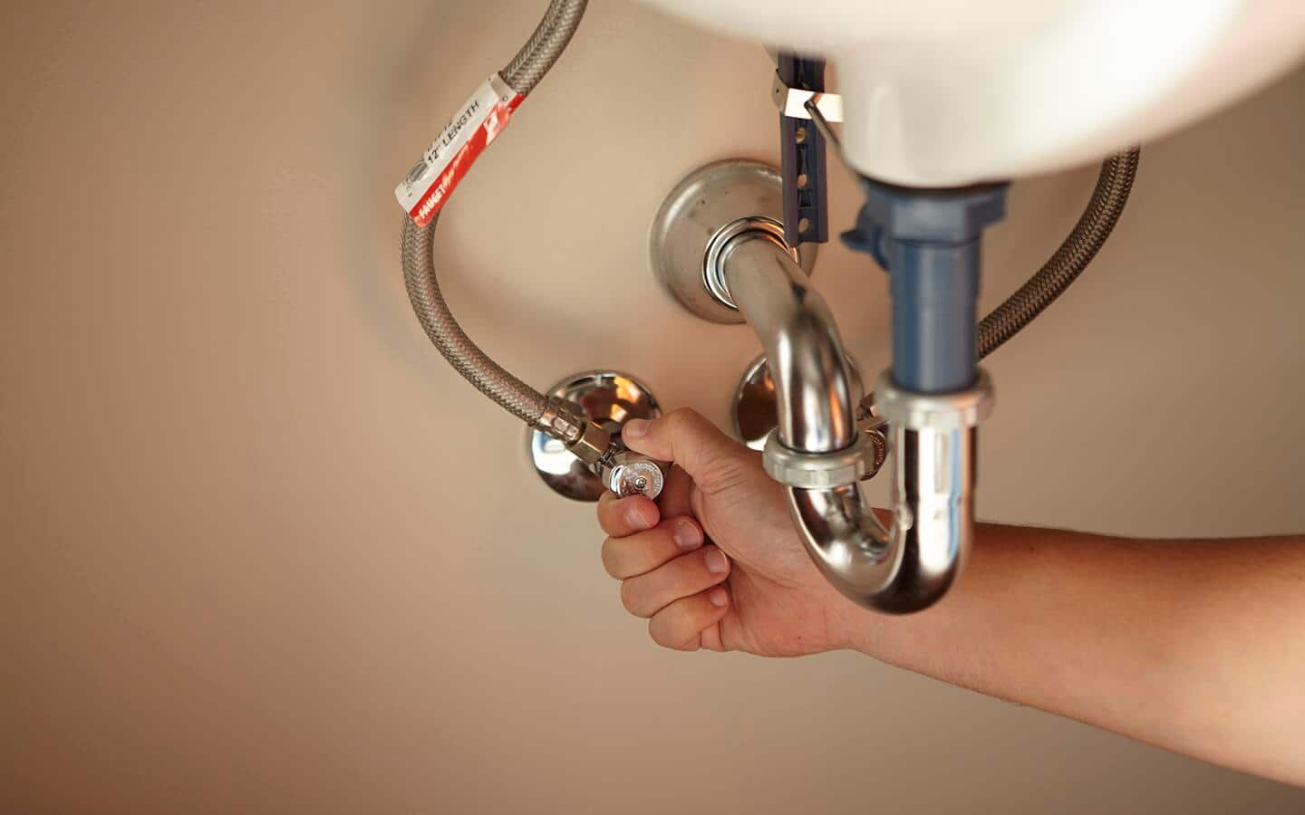 Someone adjusting a gauge to turn on water under a sink. Someone adjusting a gauge to turn on water under a sink.