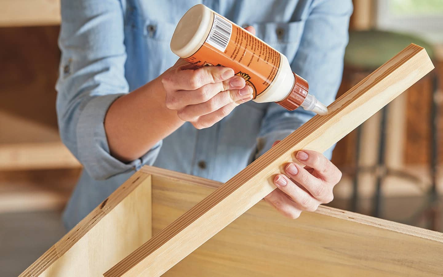 A person applies wood glue to one of the corner braces. A person applies wood glue to one of the corner braces.