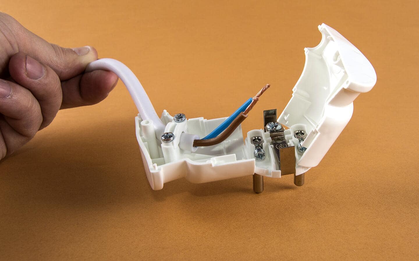 A person inserts new wiring into a white self-connecting plug. A person inserts new wiring into a white self-connecting plug.