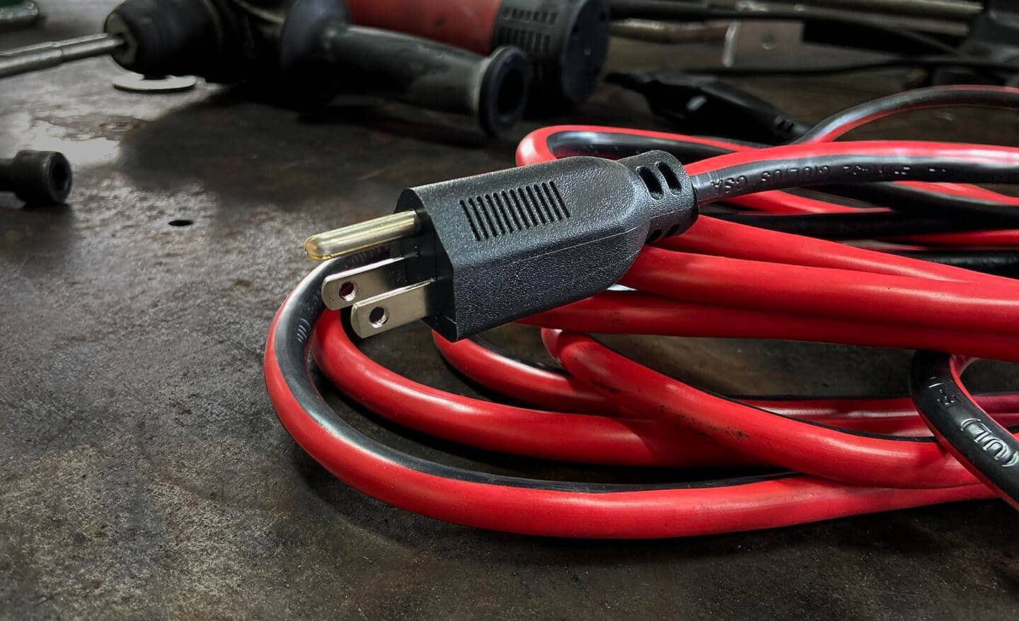 A coiled red extension cord rests on the ground.