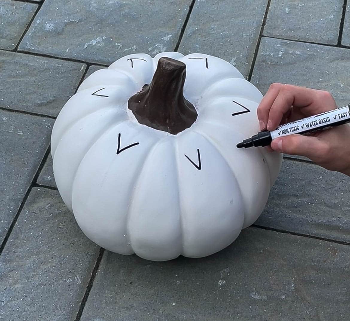 A person drawing on a pumpkin.