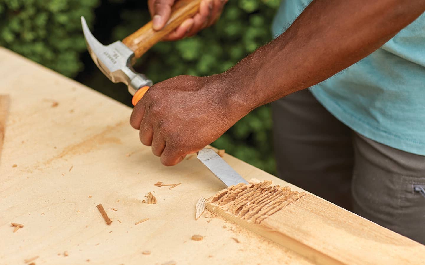 A person uses a chisel to cut the joints into a board. 