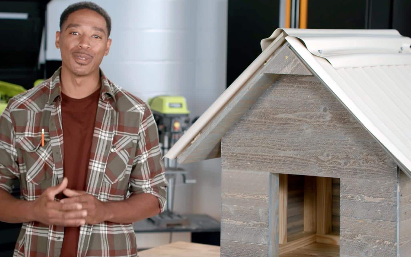 An individual standing next to the dog house they've completed.