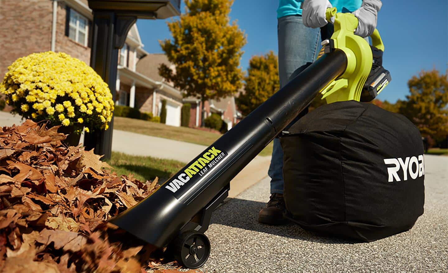 A person uses a leaf blower with a mulching bag to collect leaves.