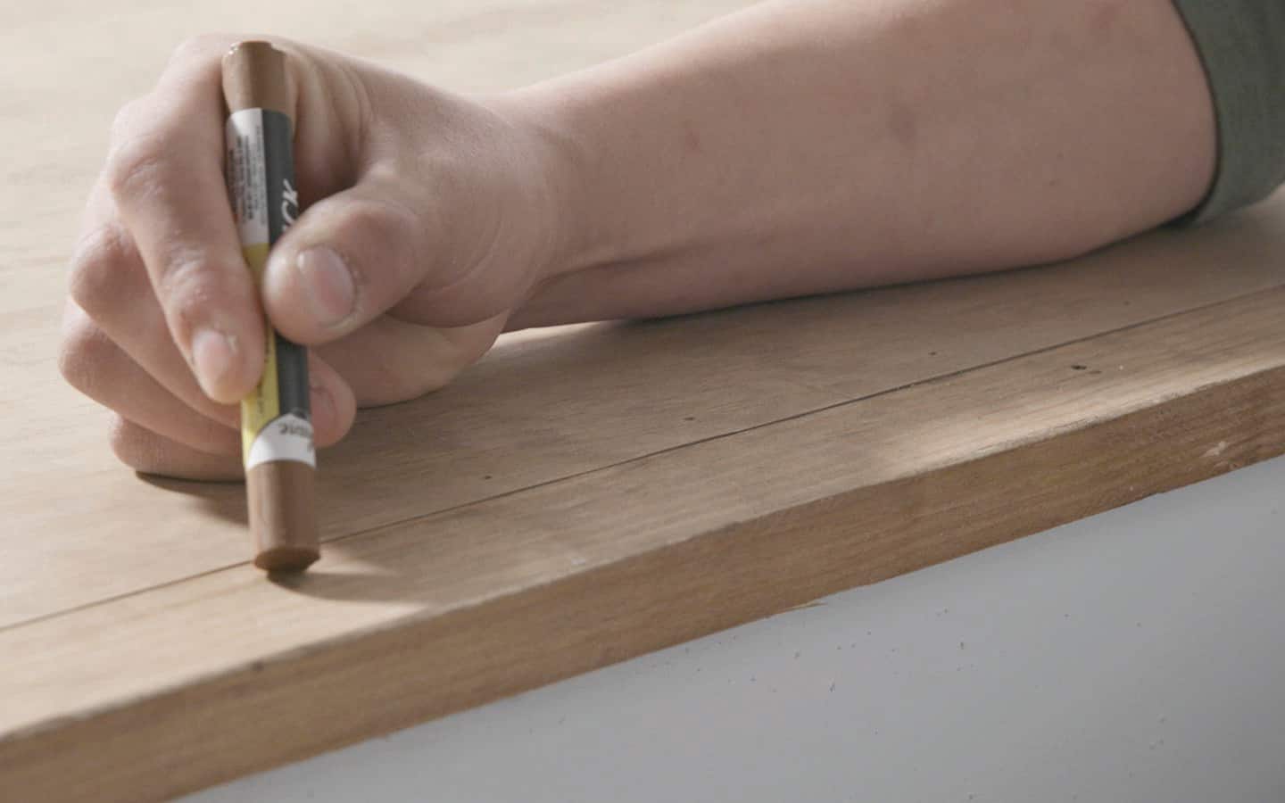 A person filling in holes using a wax stick A person filling in holes using a wax stick