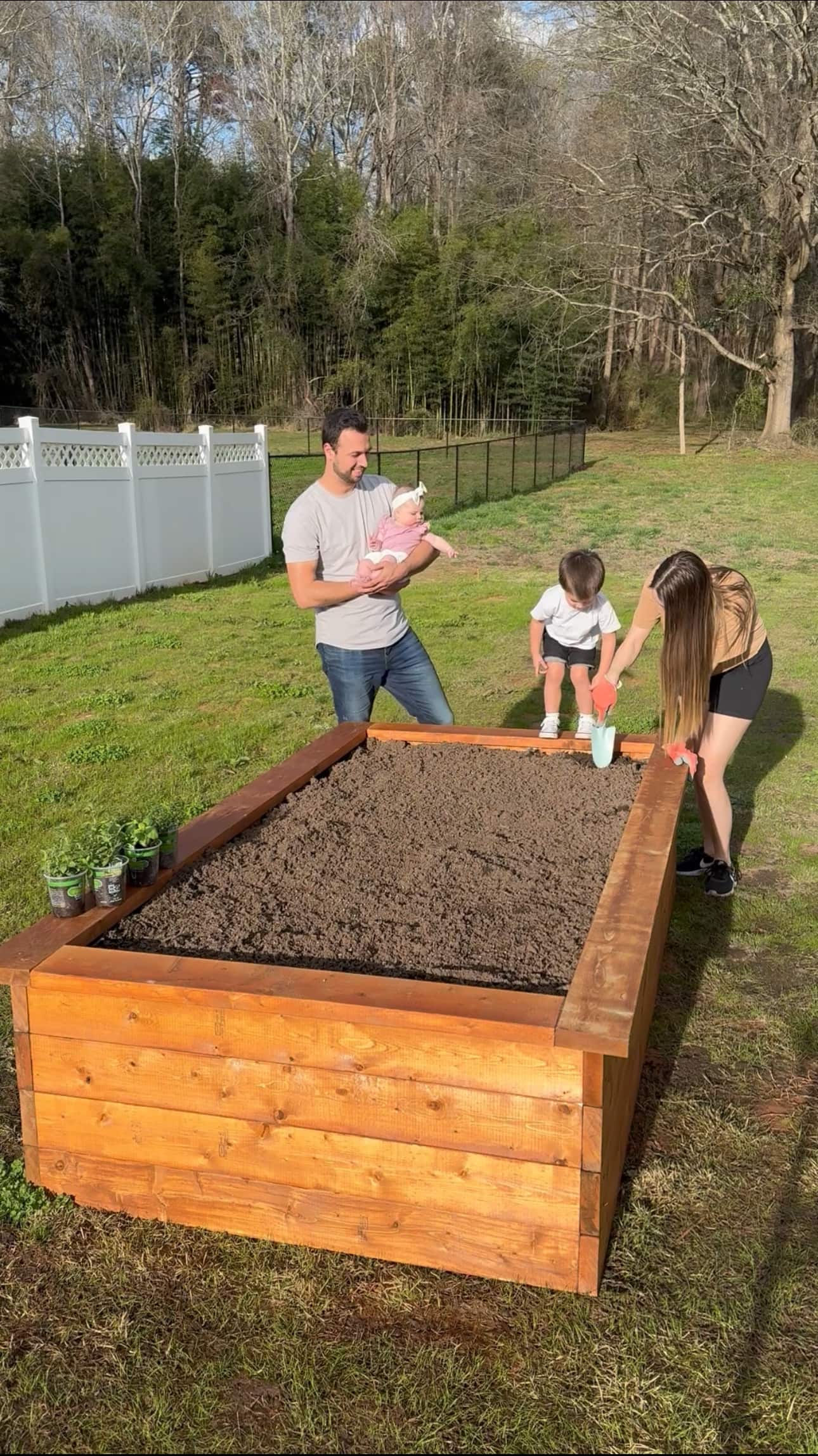 Clayton and his family stand and plant goods in their finished raised garden bed