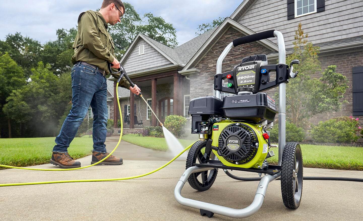 A man uses a gas powered washer to clean his sidewalks.