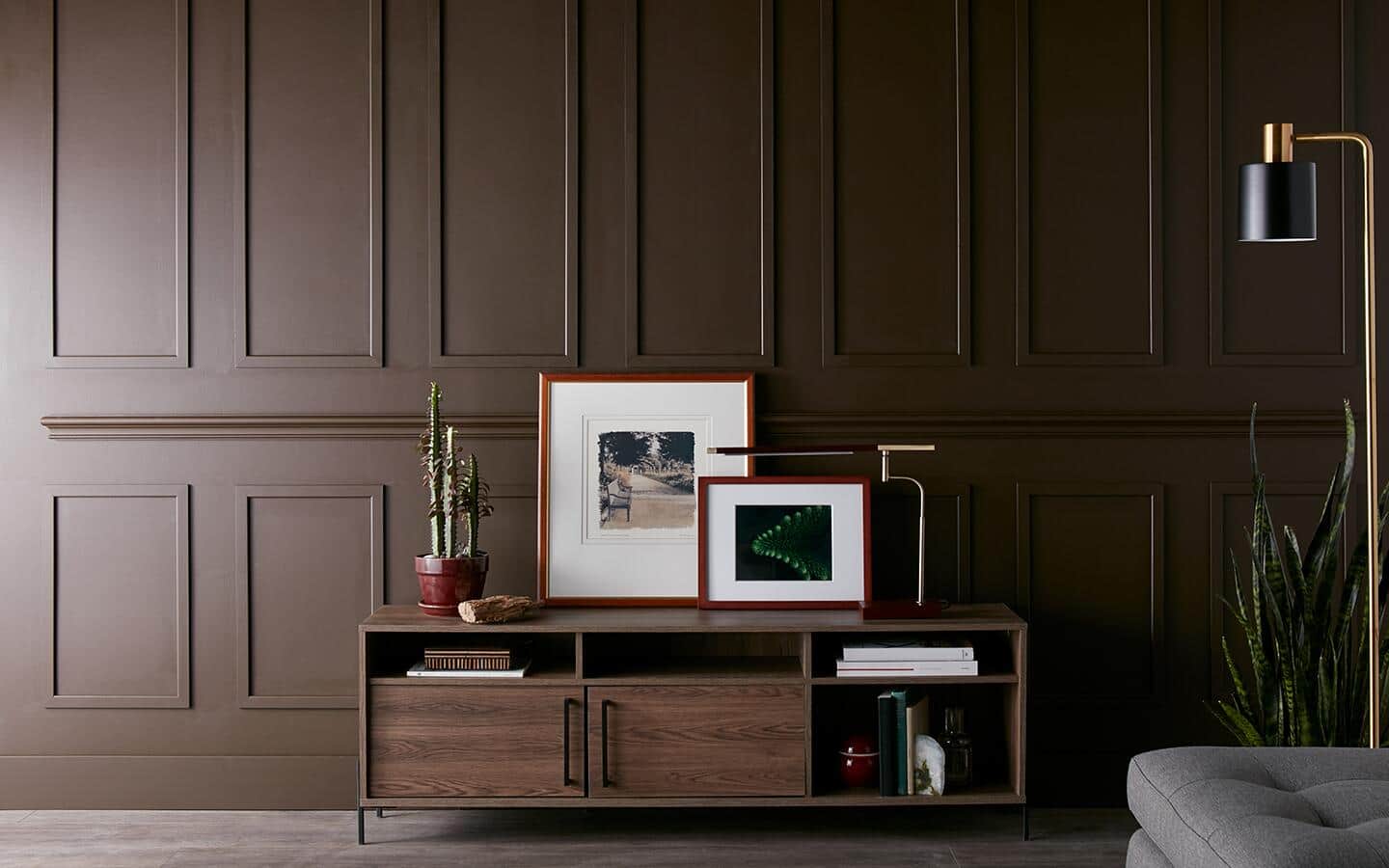 A brown room filled with storage, paintings, and a lamp. A brown room filled with storage, paintings, and a lamp.