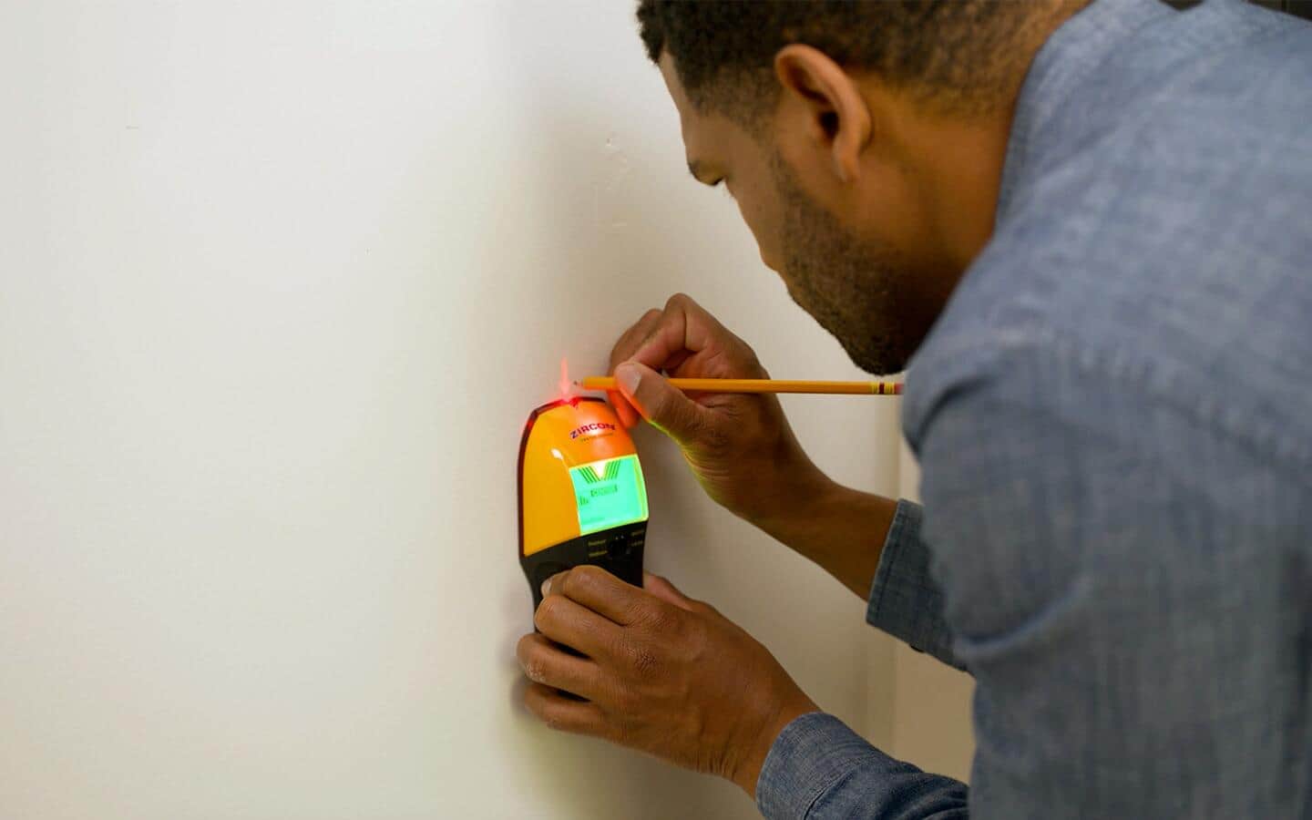 A man with a stud finder marking where a towel bar will hang.  A man with a stud finder marking where a towel bar will hang.