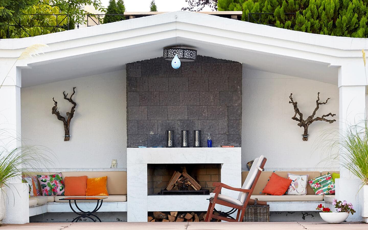 A white-marbled outdoor fireplace built in the center of a patio sofa.